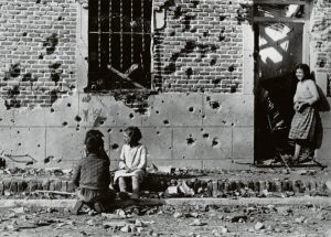 Los niños juegan ajenos al horror de la guerra ante la fachada destrozada por la metralla del número 10 de la calle Peironcely, noviembre-diciembre 1936.